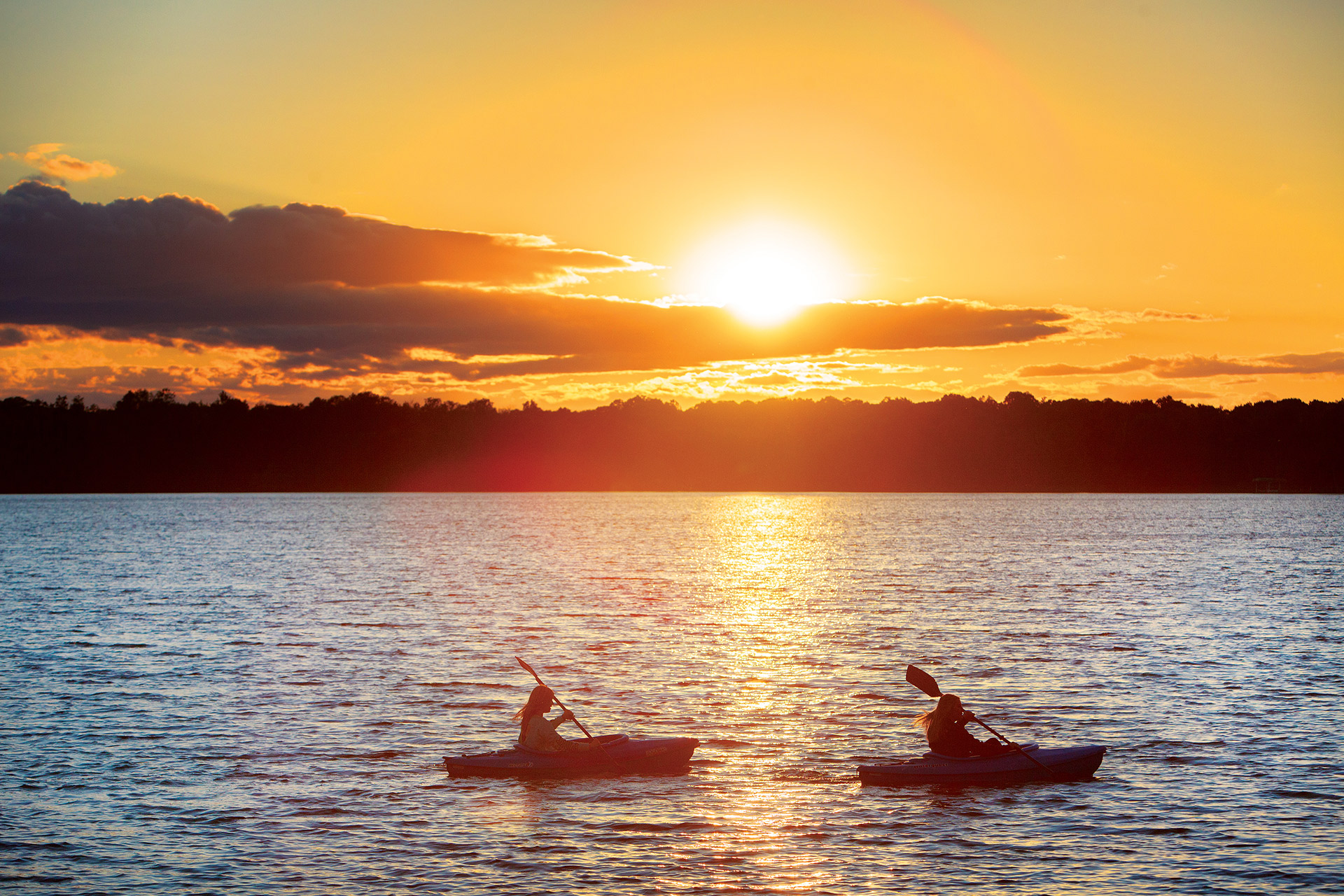 Two canoers paddling on the lake at sunset